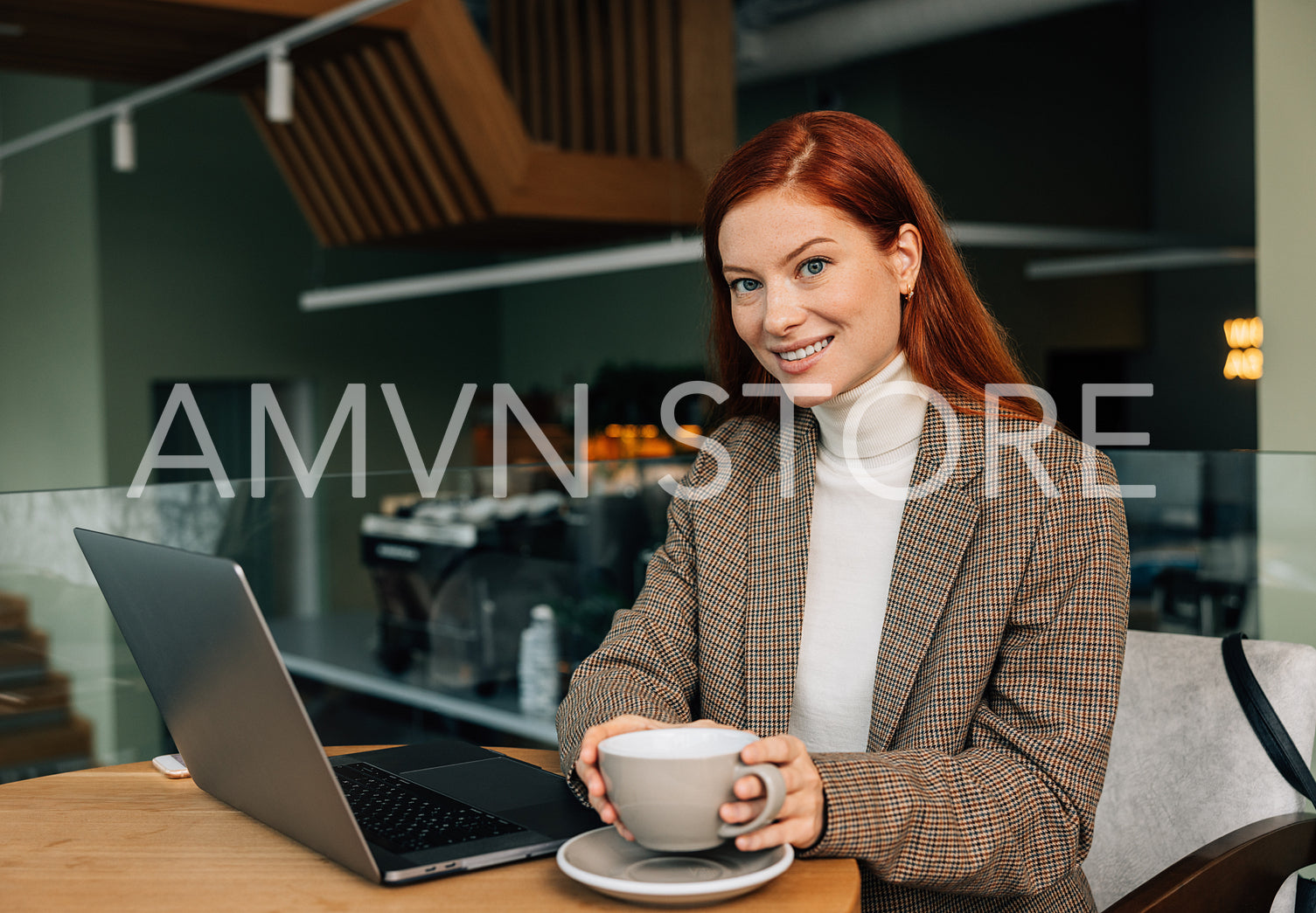 Beautiful businesswoman with ginger hair looking at camera while holding a cup 