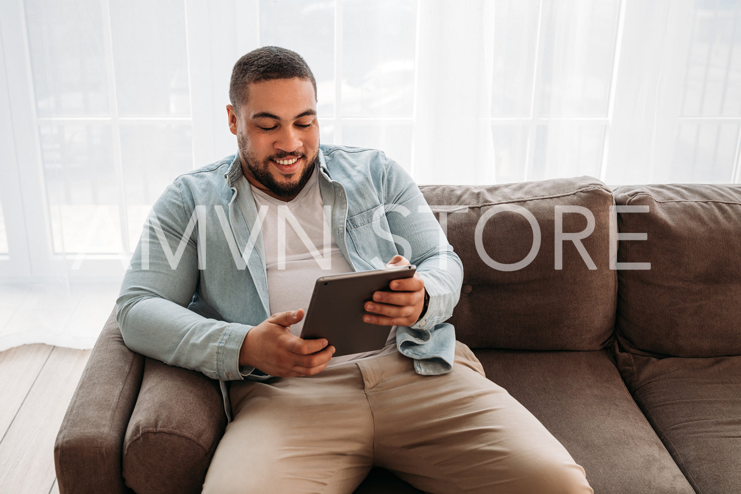 Smiling man with digital tablet sitting on a sofa at home	