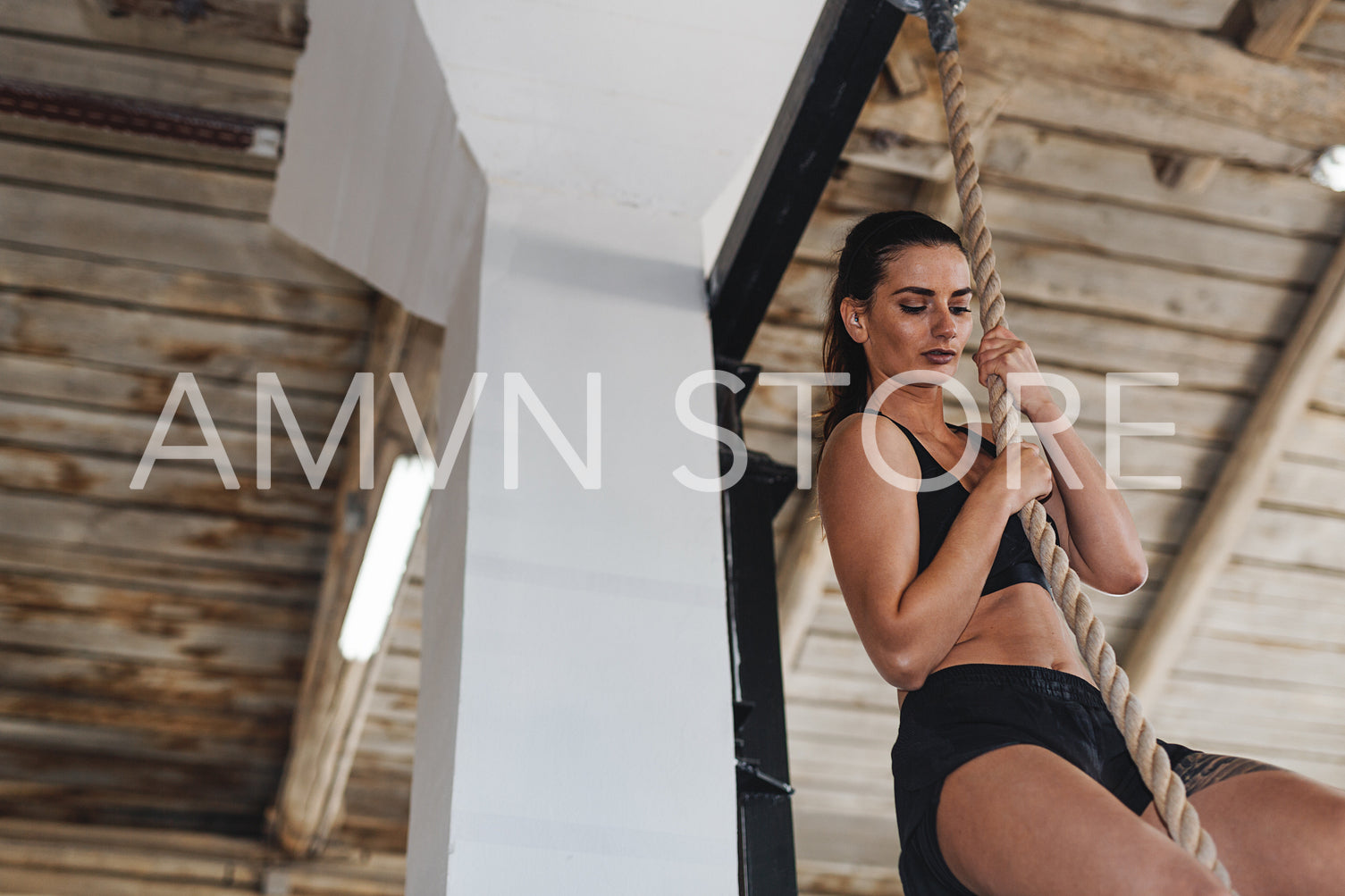 Strong determined woman climbing rope at gym	