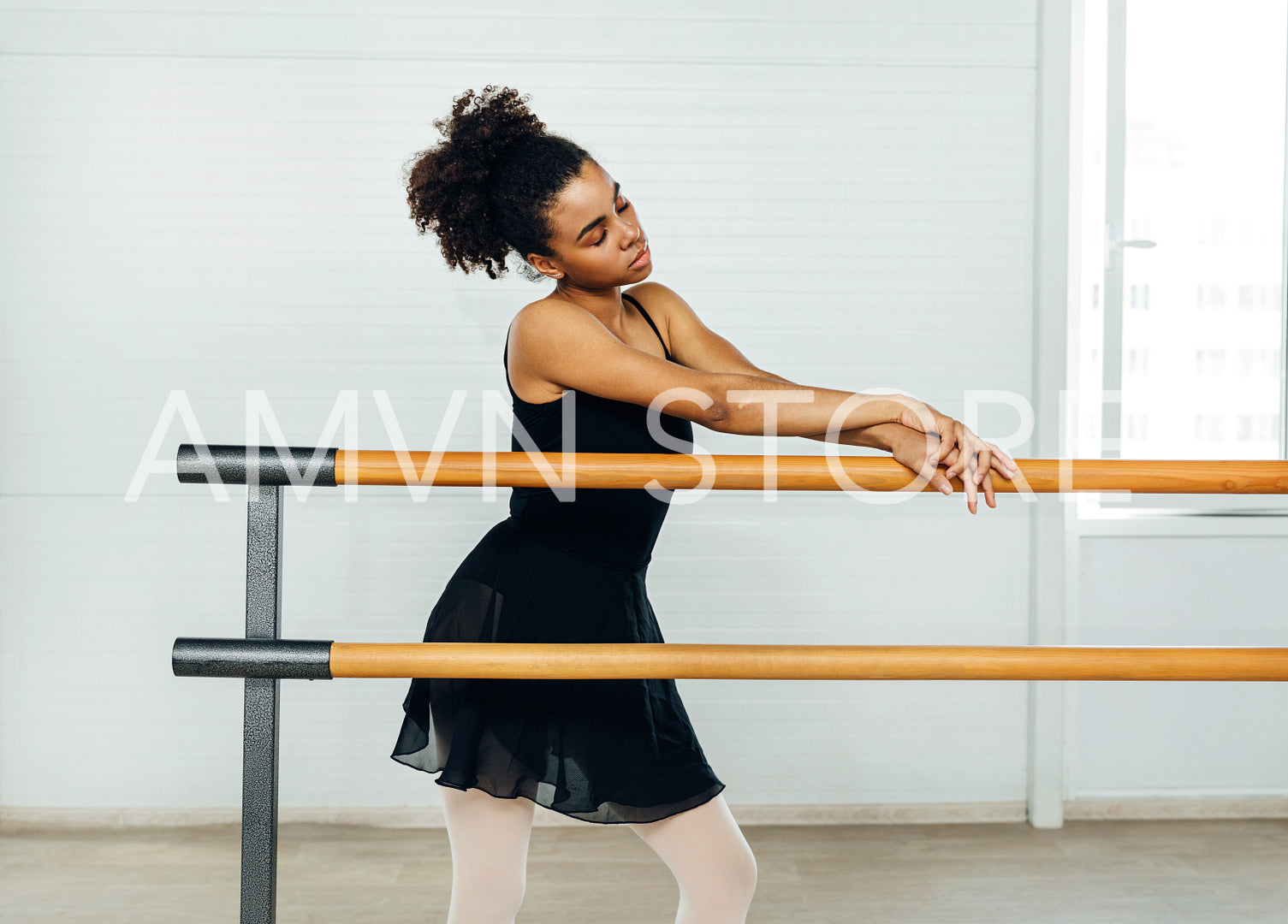 Young woman standing with closed eyes and leaning on barres at the dance studio	