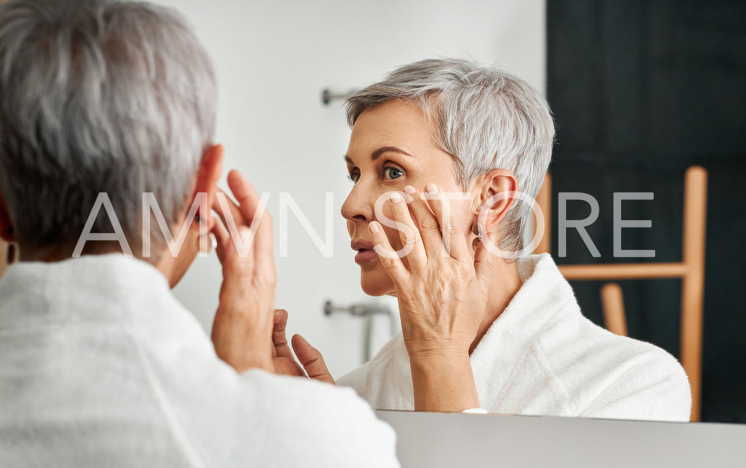 Close up of mature woman applying cream with hand in front of a mirror	