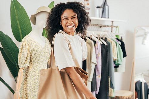 Happy woman with shopping bag looking at camera. Cheerful female standing in a clothing store.