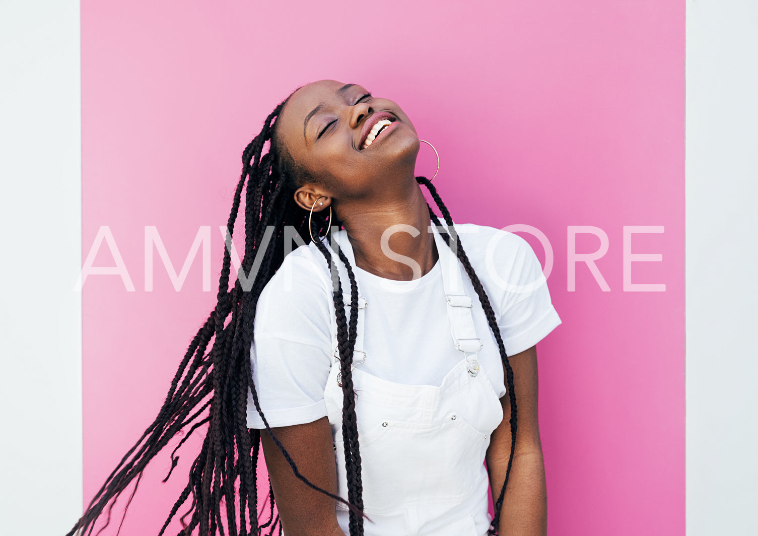 Happy woman with braids standing at pink wall outdoors with closed eyes