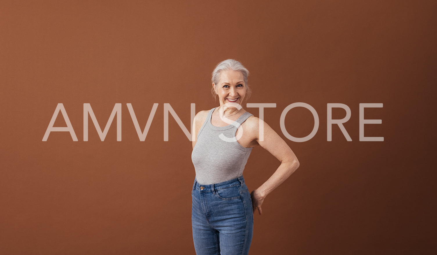 Portrait of a mature woman in casuals standing at brown background in studio