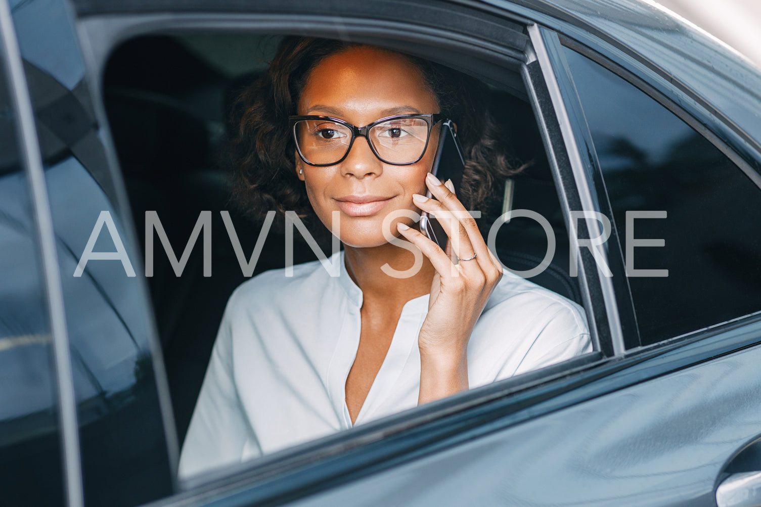 Young woman talking on the cellphone while sitting on back seat of a taxi	