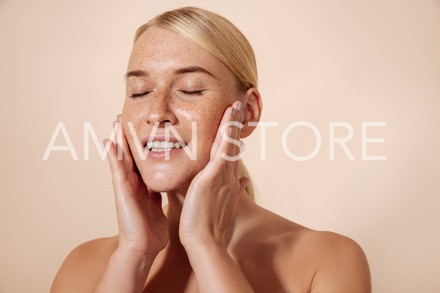 Studio shot of a young blonde woman touching her face with close