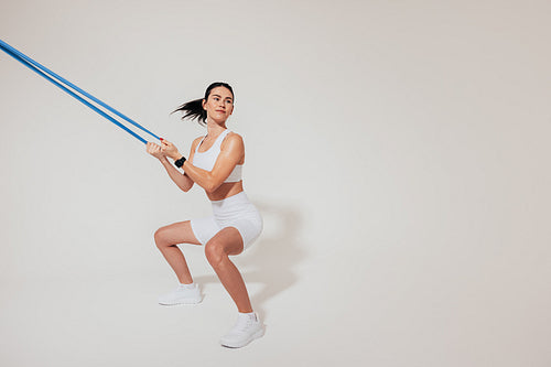 Young slim woman doing sit-ups and using a resistance band