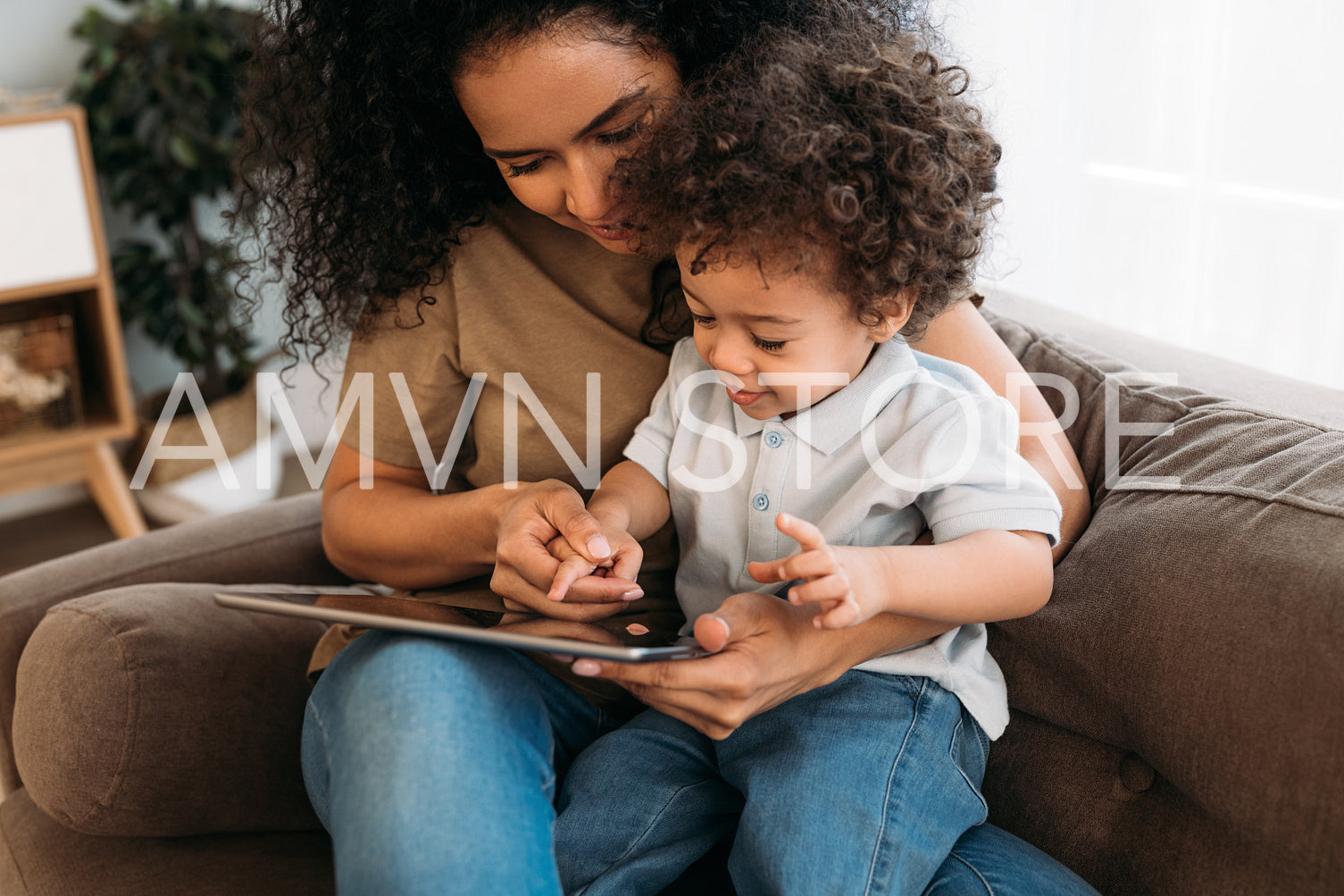 Young mother helping her little son with learning app