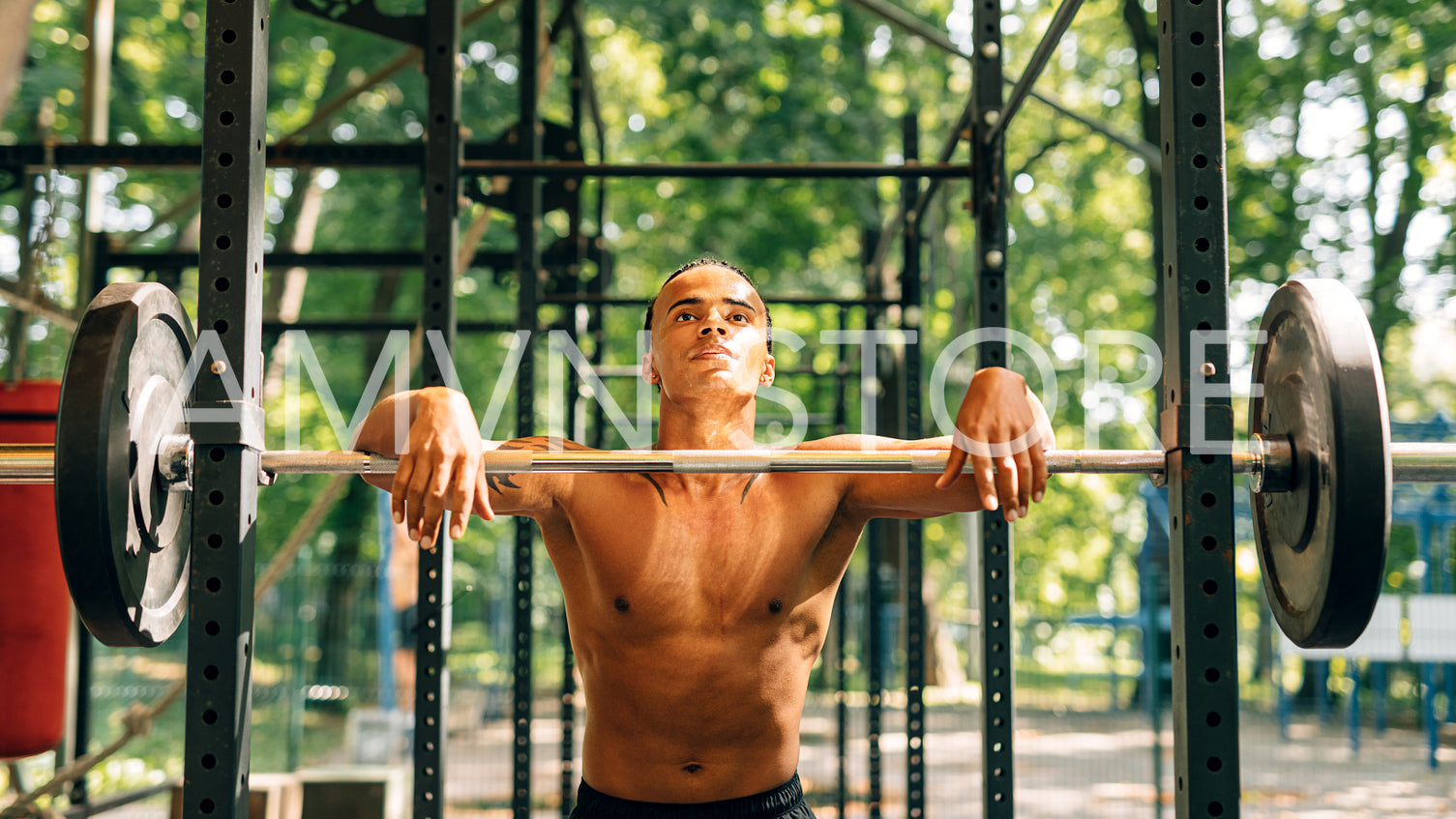 Exhausted and sweated athlete relaxing outdoors. Young sportsman resting at power rack.	