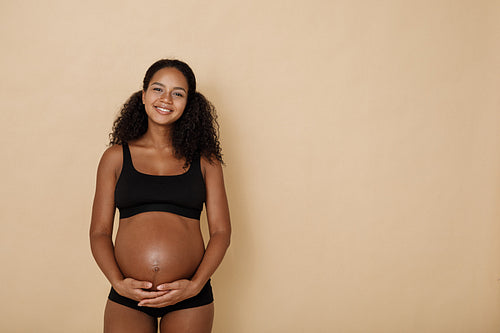 Studio portrait of pregnant woman holding her belly