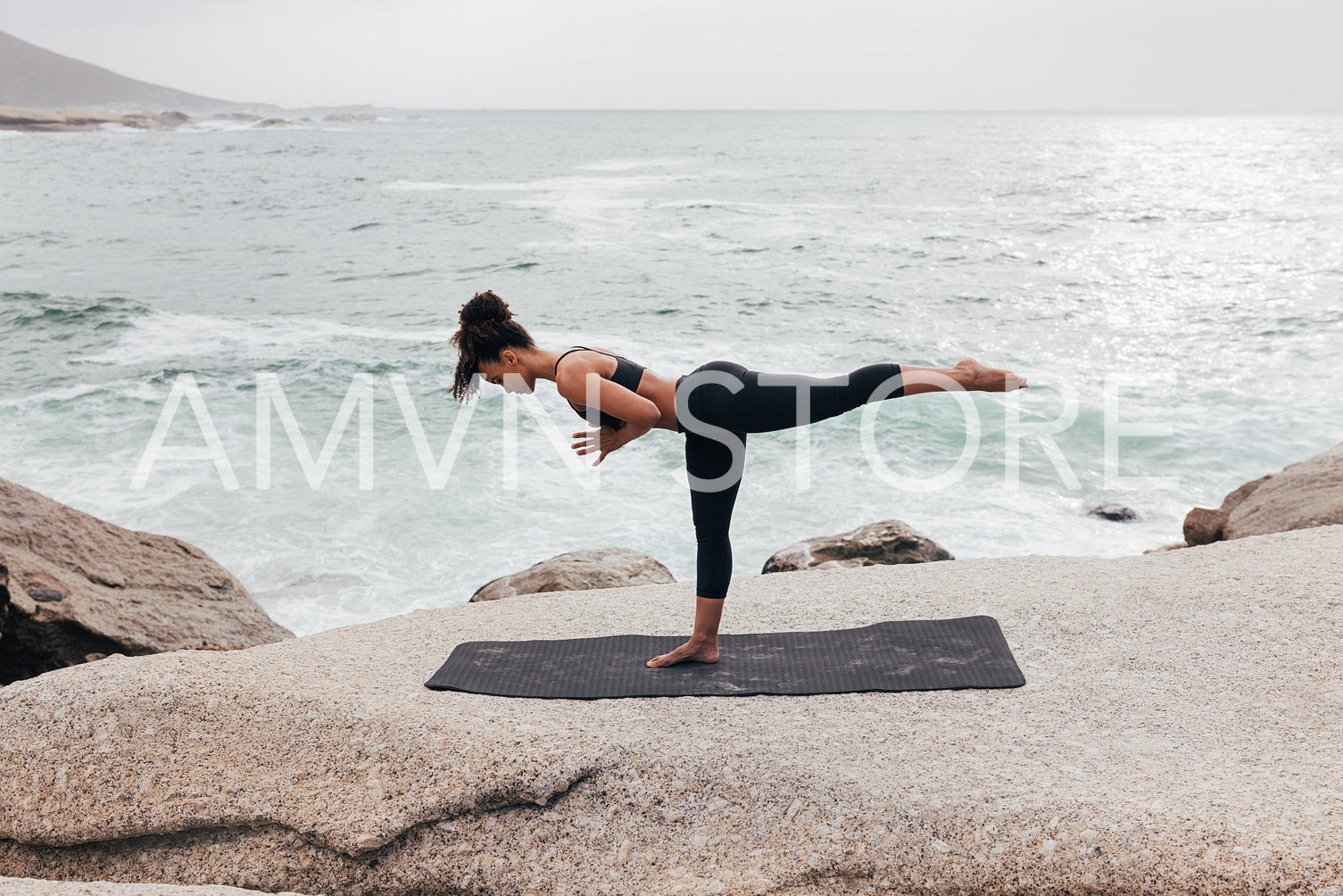 Side view of young woman practicing yoga. Female in sportswear exercising at sunset on a shore.