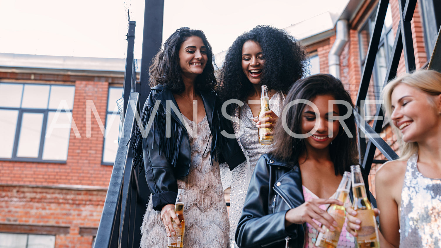 Four female friends walking with bottles of beer	