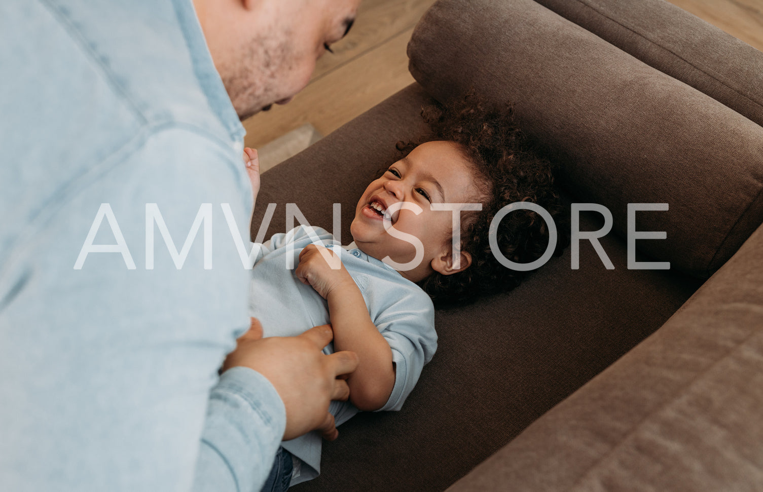 Close up of a father tickling laughing young boy on sofa