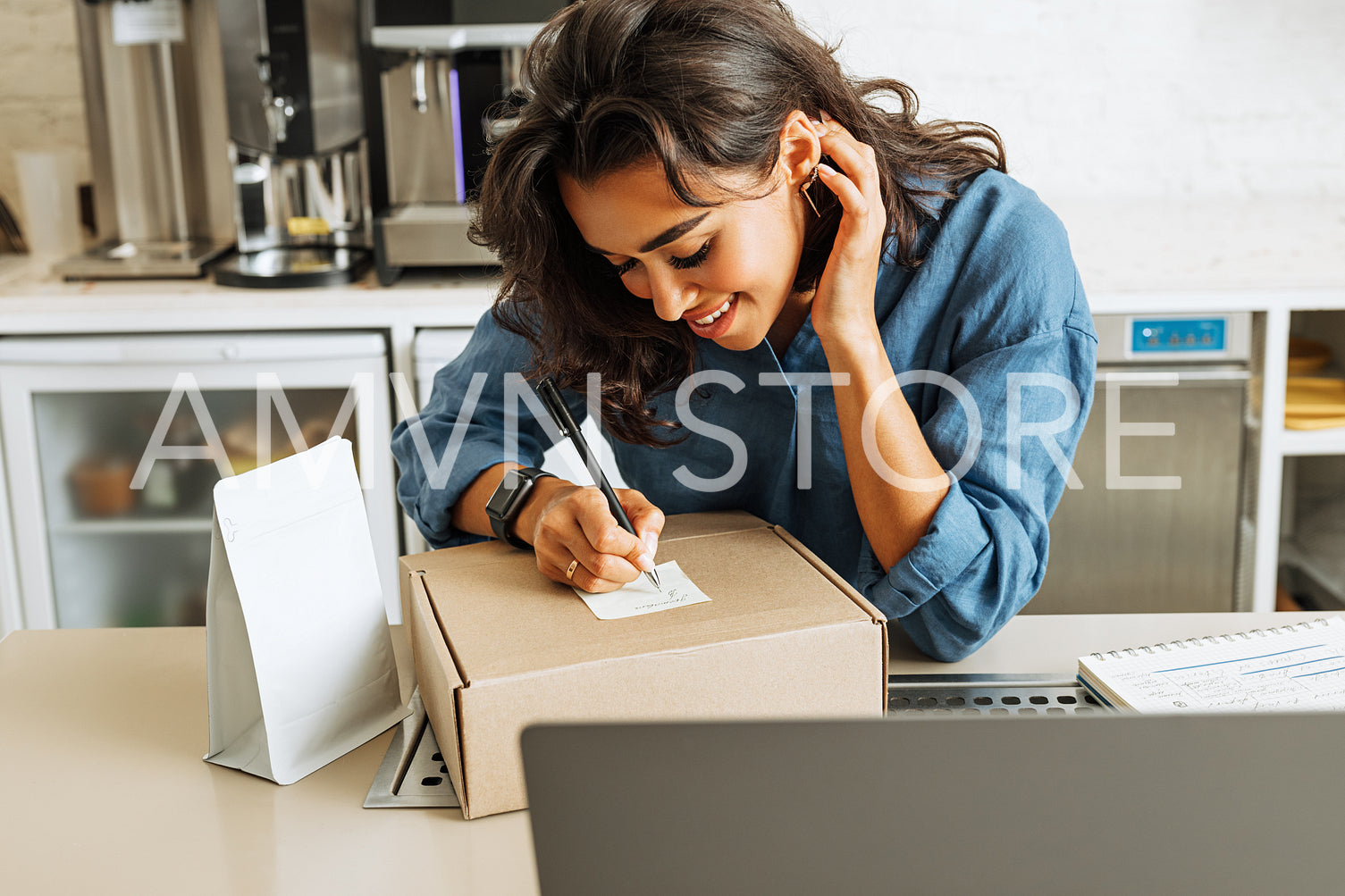 Smiling business owner taking notes on cardboard box before shipping