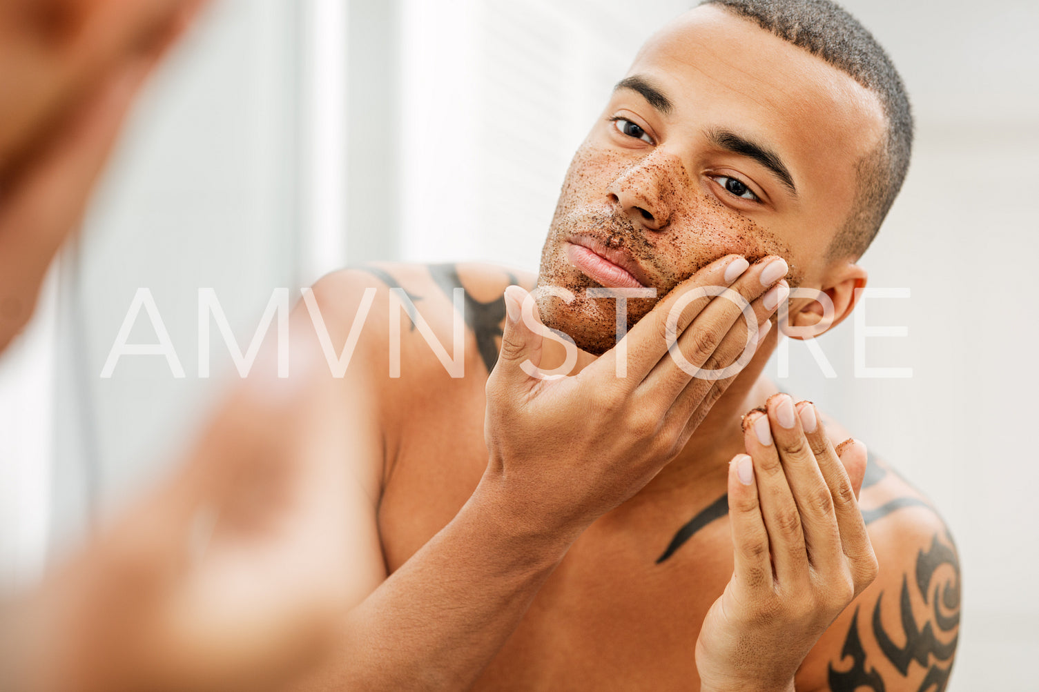 Handsome man applying natural scrub in front of a mirror	