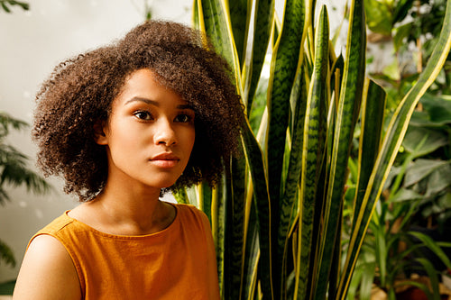 Portrait of beautiful young woman sitting near sansevieria leafs