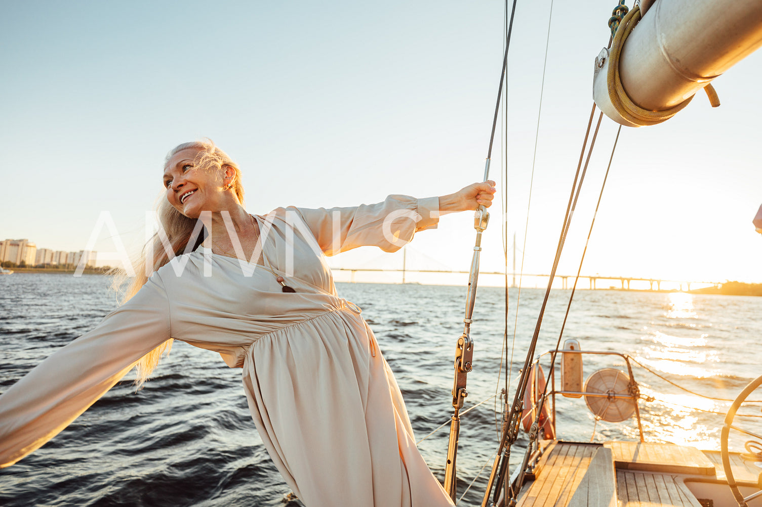 Cheerful senior woman in long dress enjoying vacation on private sailboat	