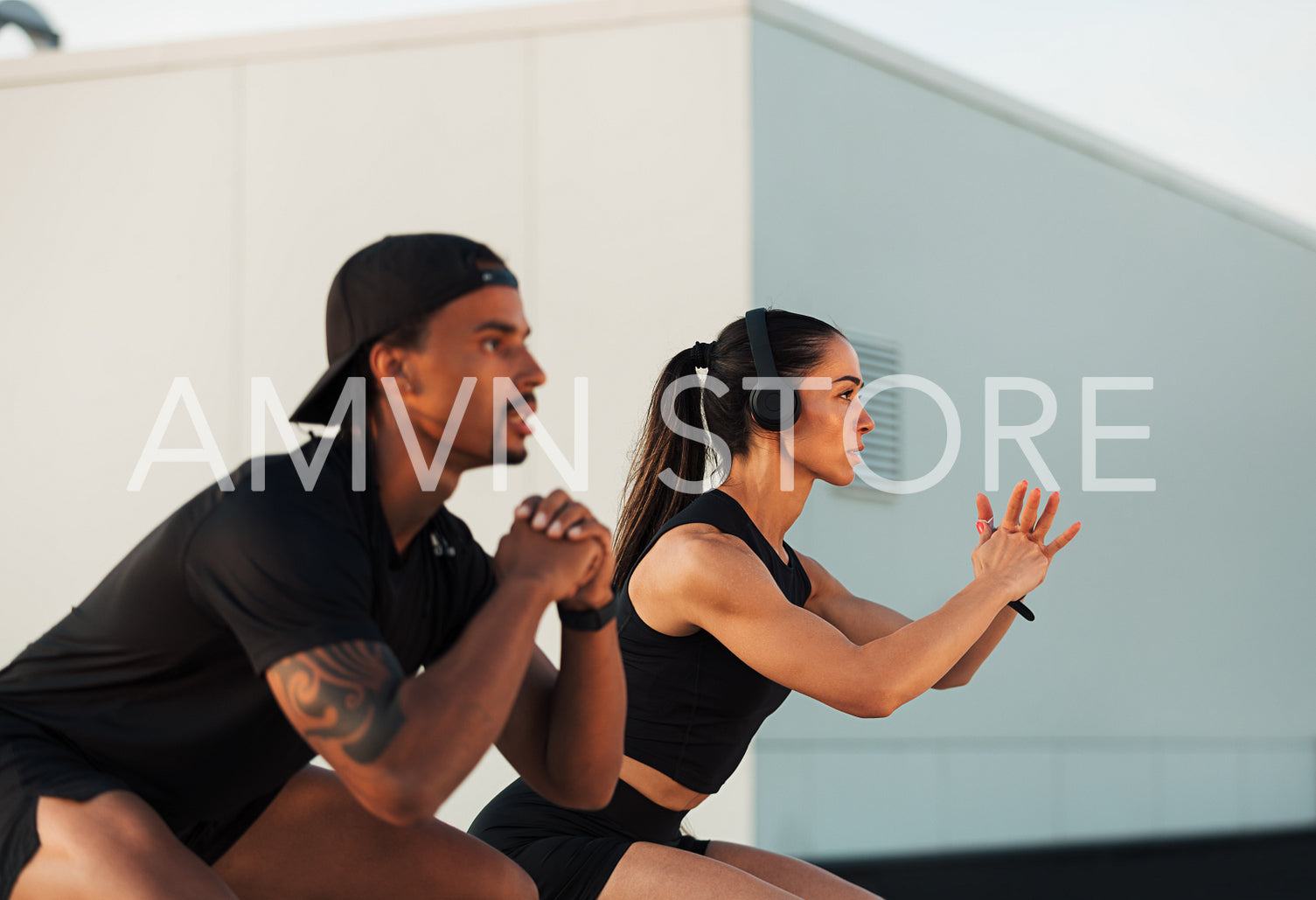 Two athletes are doing sit-ups on a rooftop. Fitness couple exercising together.