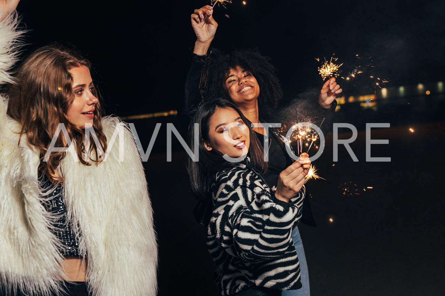 Group of multi ethnic girls with sparklers walking on street at night	