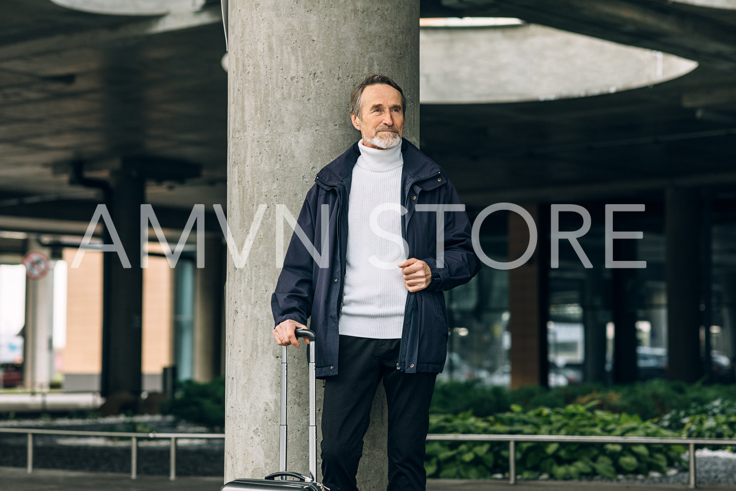 Stylish senior tourist standing outdoors with suitcase and looking away	