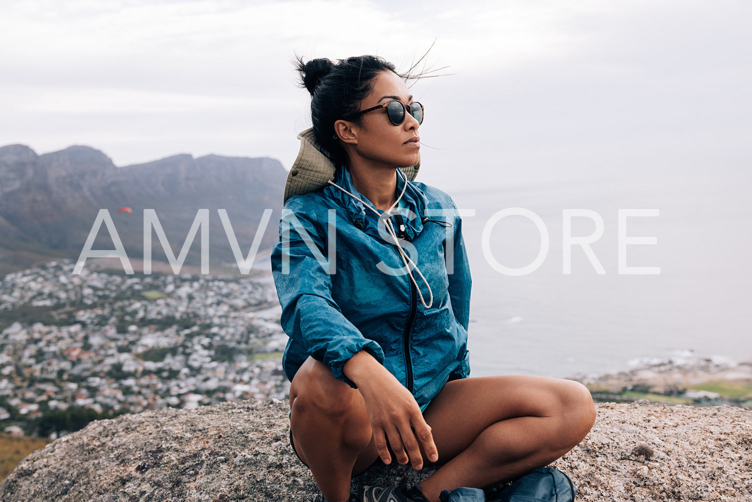 Young woman hiker relaxing and enjoying the view sitting on a cliff