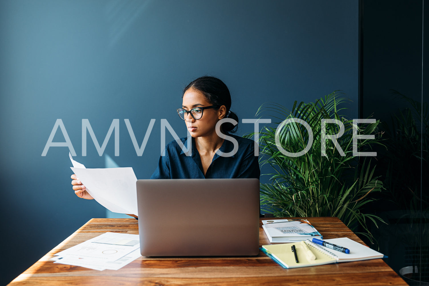 Serious businesswoman sitting by a desk and holds documents	