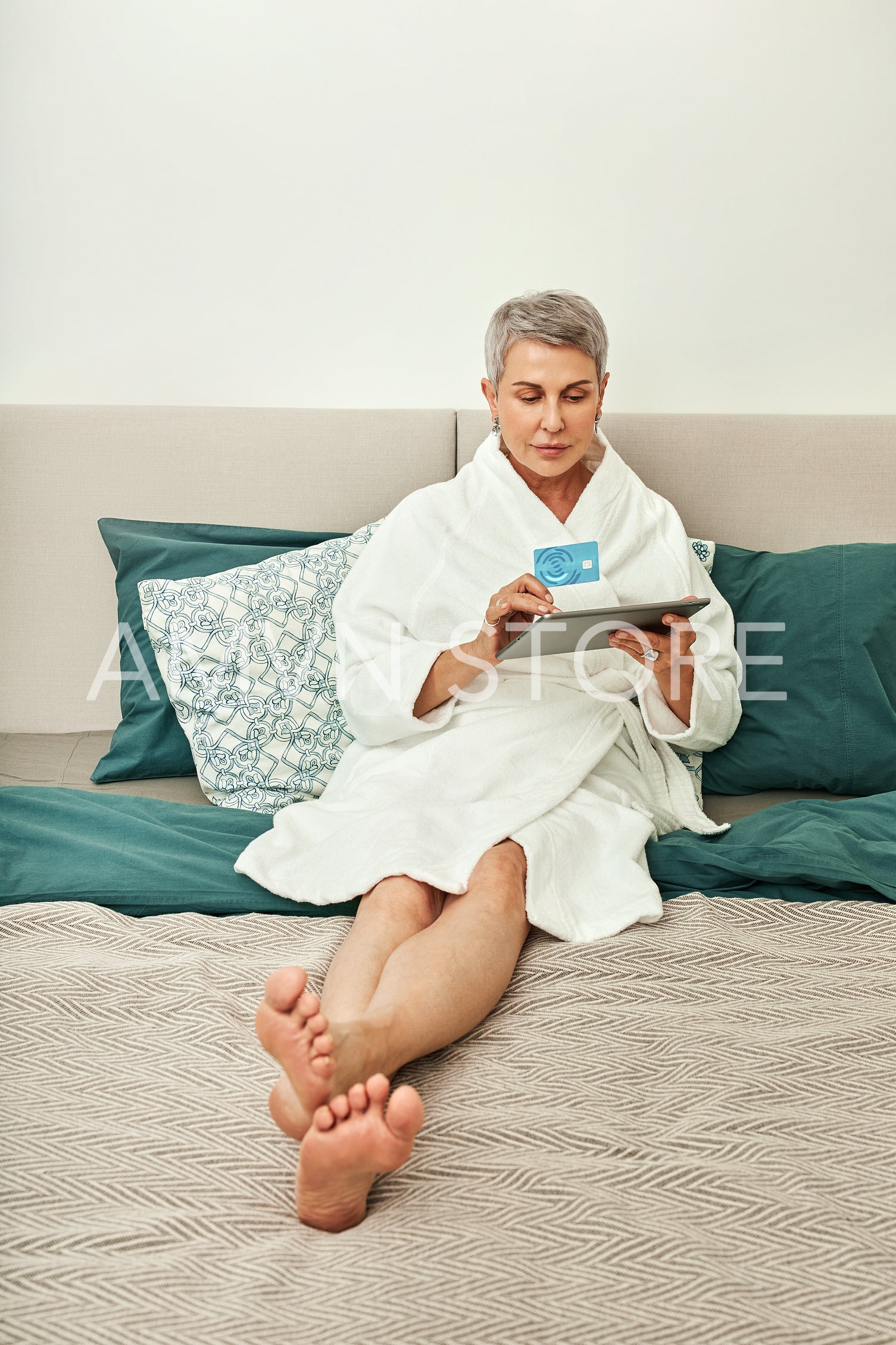 Senior woman with grey hair making an online purchase from bedroom	