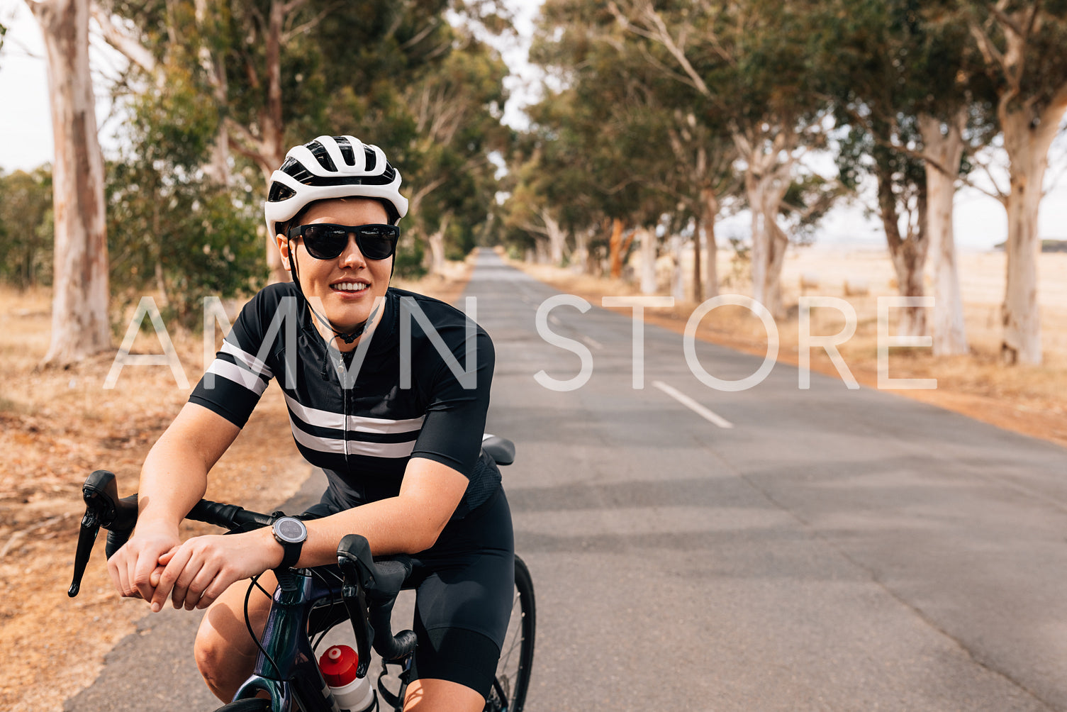 Smiling woman cyclist leaning on a handlebar of her road bike relaxing during training