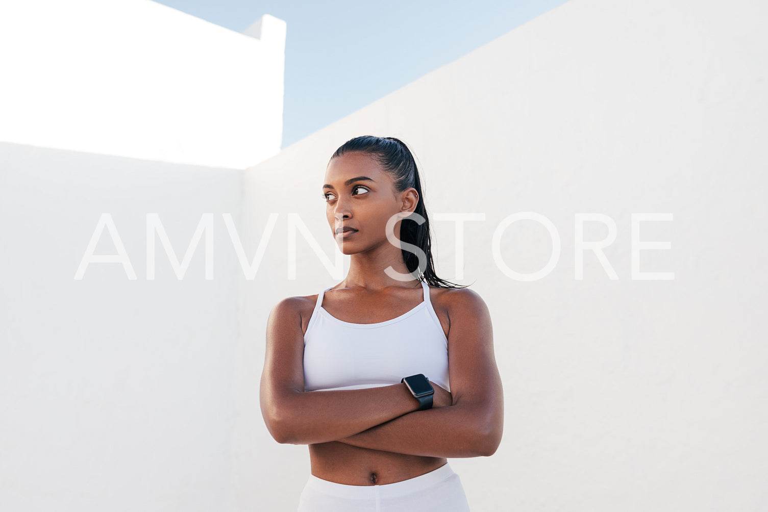 Strong and confident fitness influencer. Woman in white sports clothes with crossed hands.