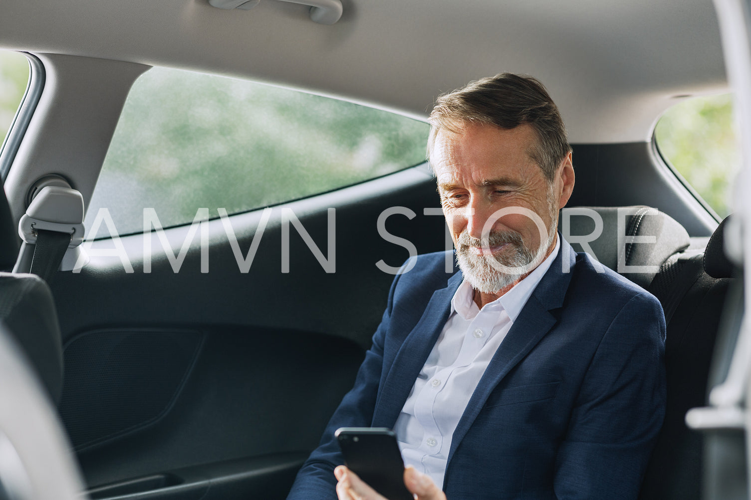 Businessman sitting in the car using a smartphone. Man checking cell phone on a backseat.	