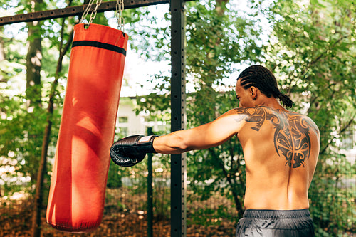 Side view of kickboxer hitting a punching bag on the sports ground