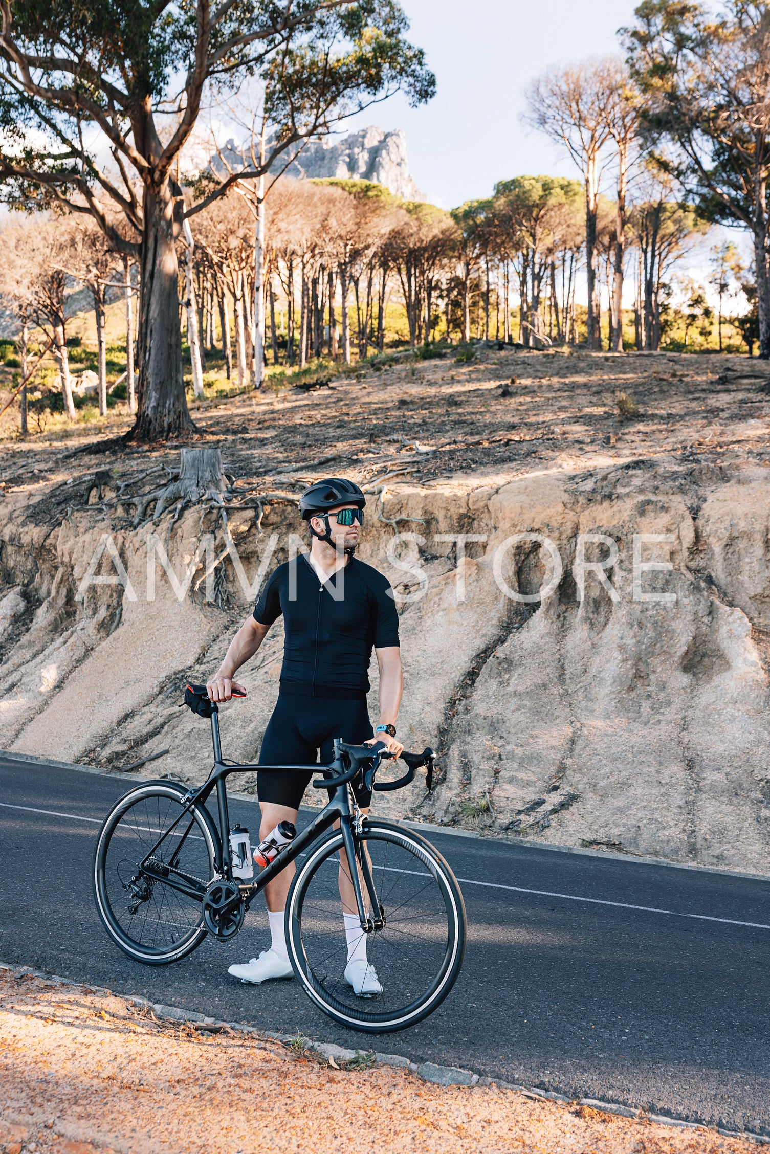 Male cyclist on a roadside with his bicycle. Professional triathlete relaxing.