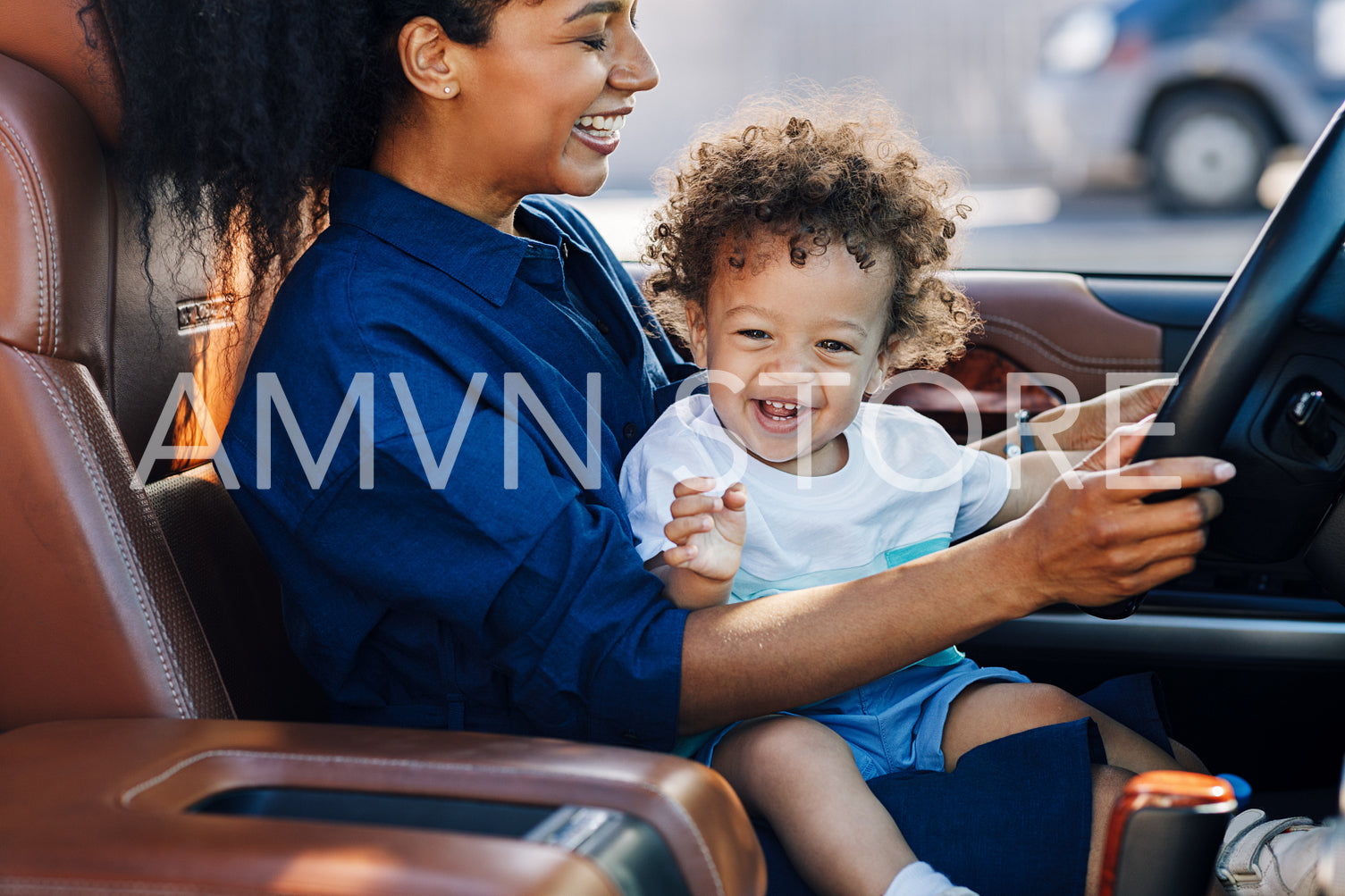 Happy mother and her son sitting on driver seat in a car	