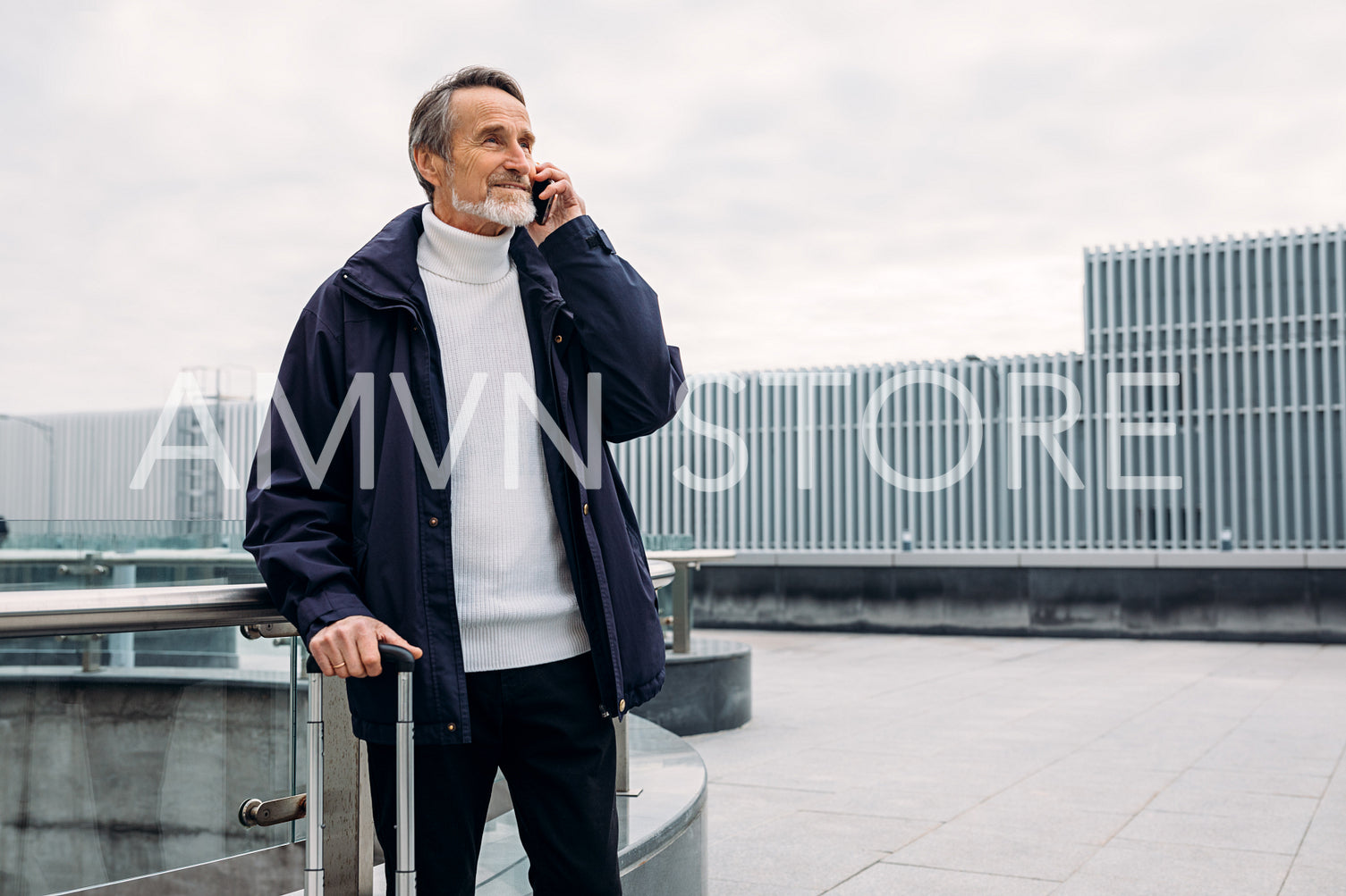 Mature male tourist standing outdoors with luggage and talking on cell phone	