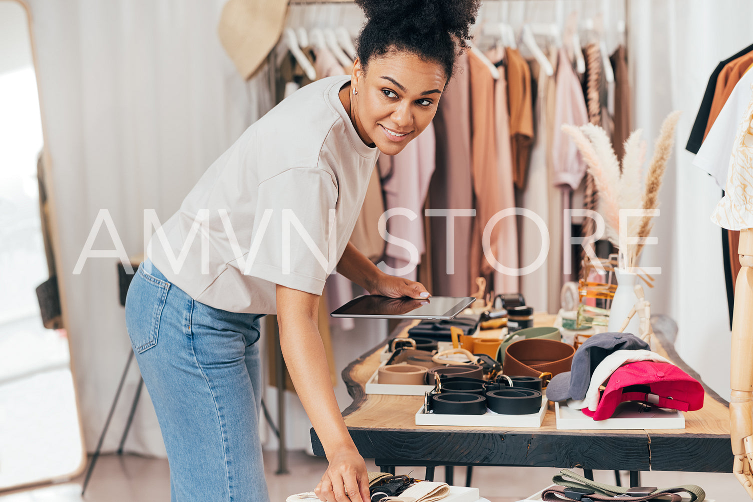 Woman working in her local clothes store. Boutique owner checking accessories holding digital tablet.