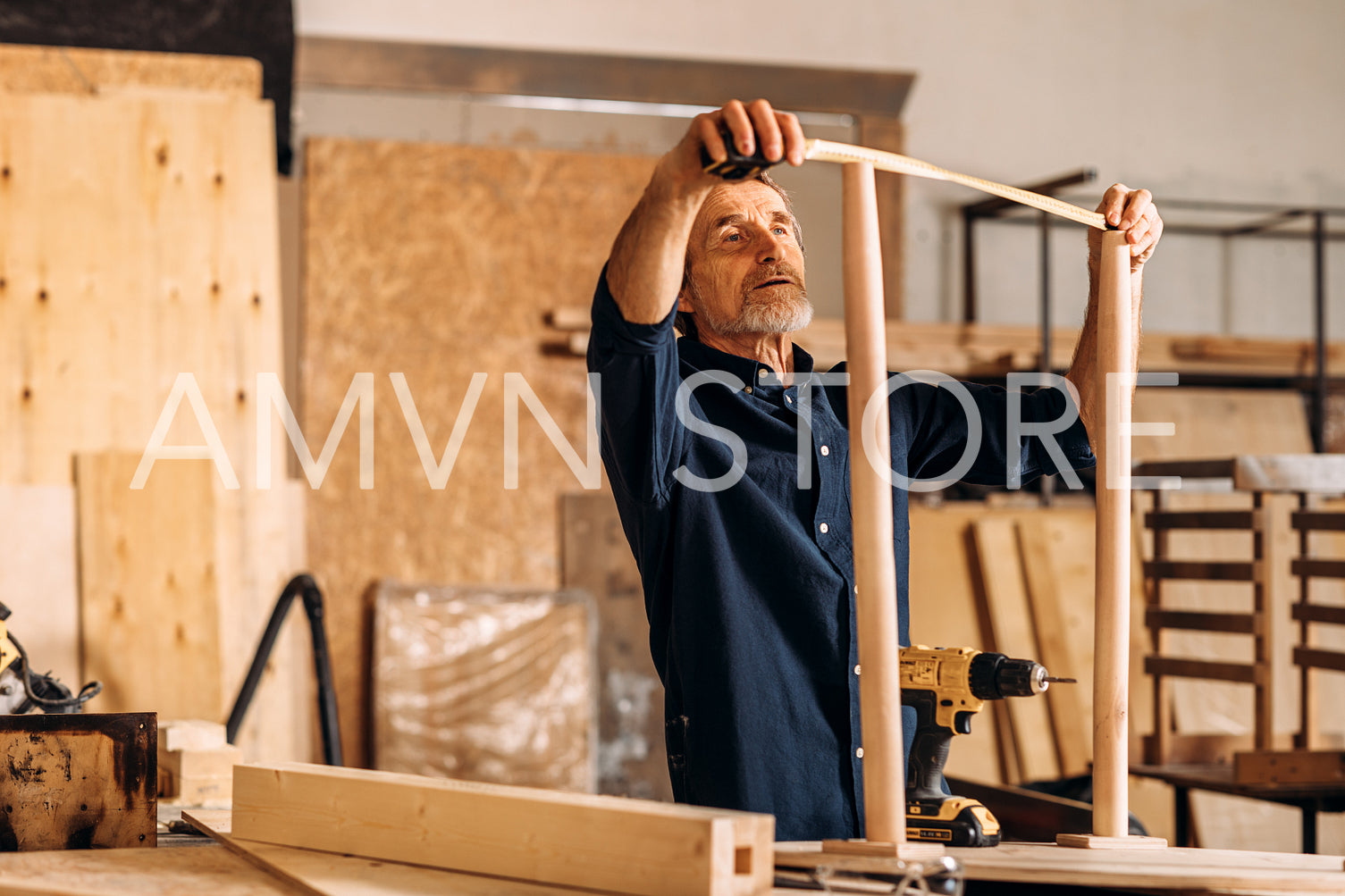 Carpenter measures the width between the legs of a table in a workshop	