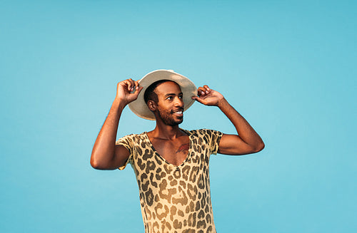 Stylish male holding his straw hat with hands and looking away