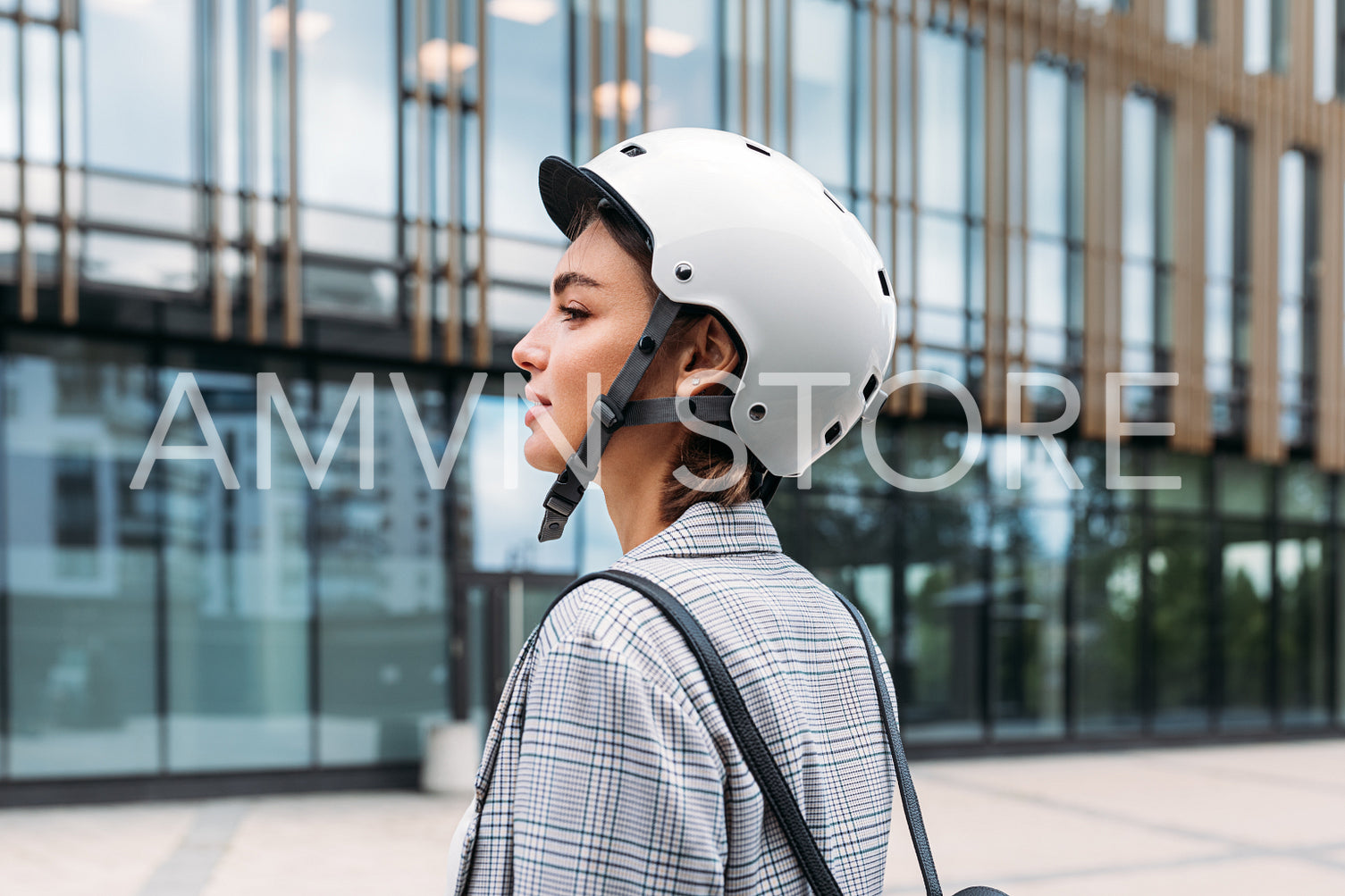 Side view of a young businesswoman wearing helmet standing outdoors near office building