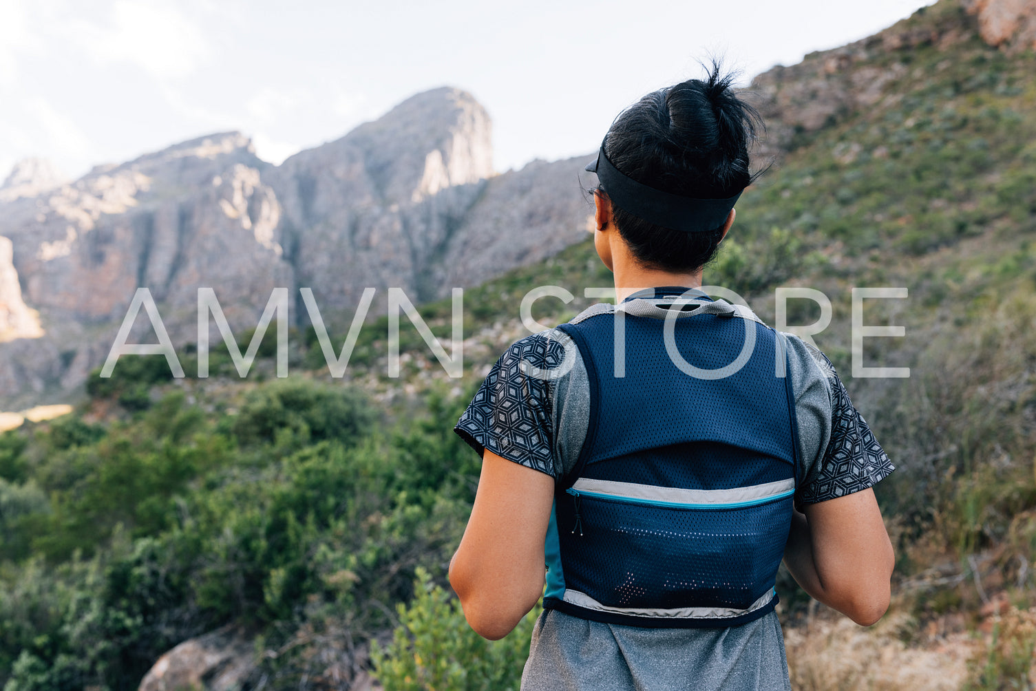 Rear view of woman hiker in sportswear standing in the valley an