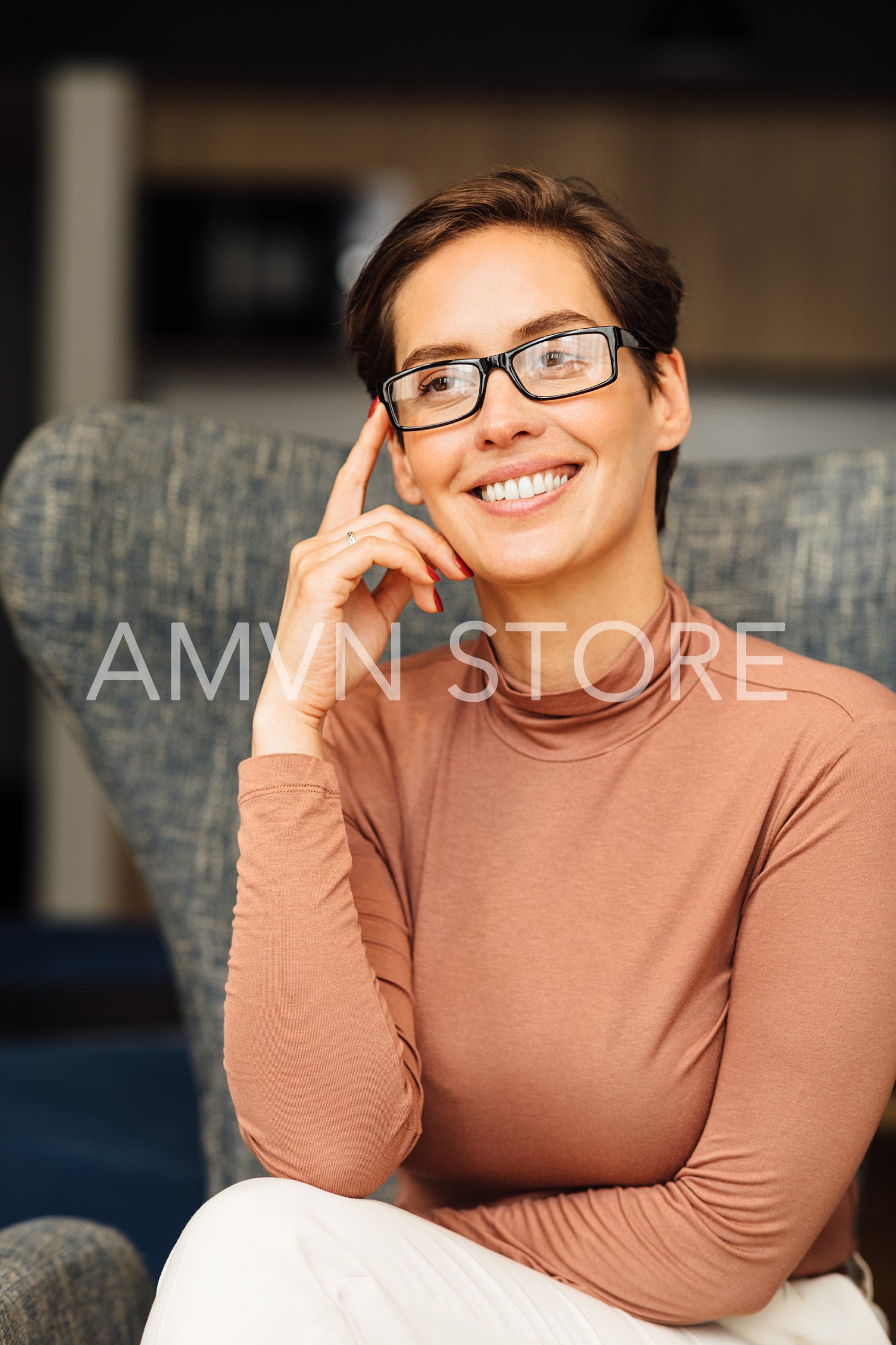 Beautiful smiling woman in eyeglasses relaxing in an armchair. Portrait of a businesswoman wearing casuals in apartment.	