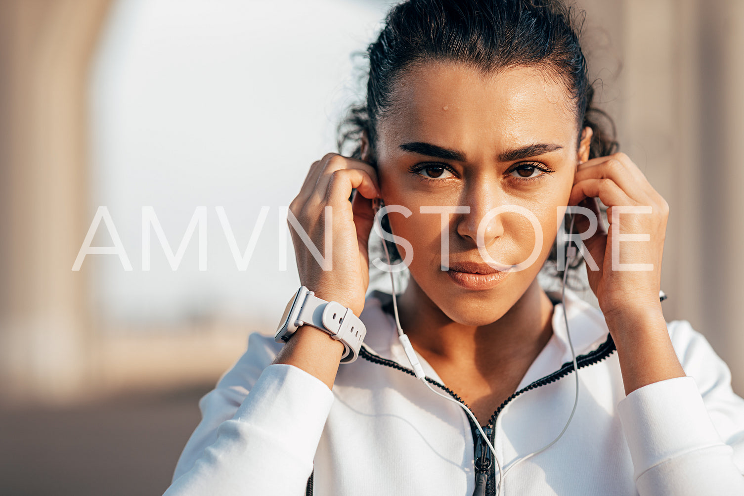 Close up portrait of sweated sportswoman adjusting her earphones during a workout	