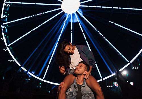 Young female and her boyfriend at night against ferris wheel