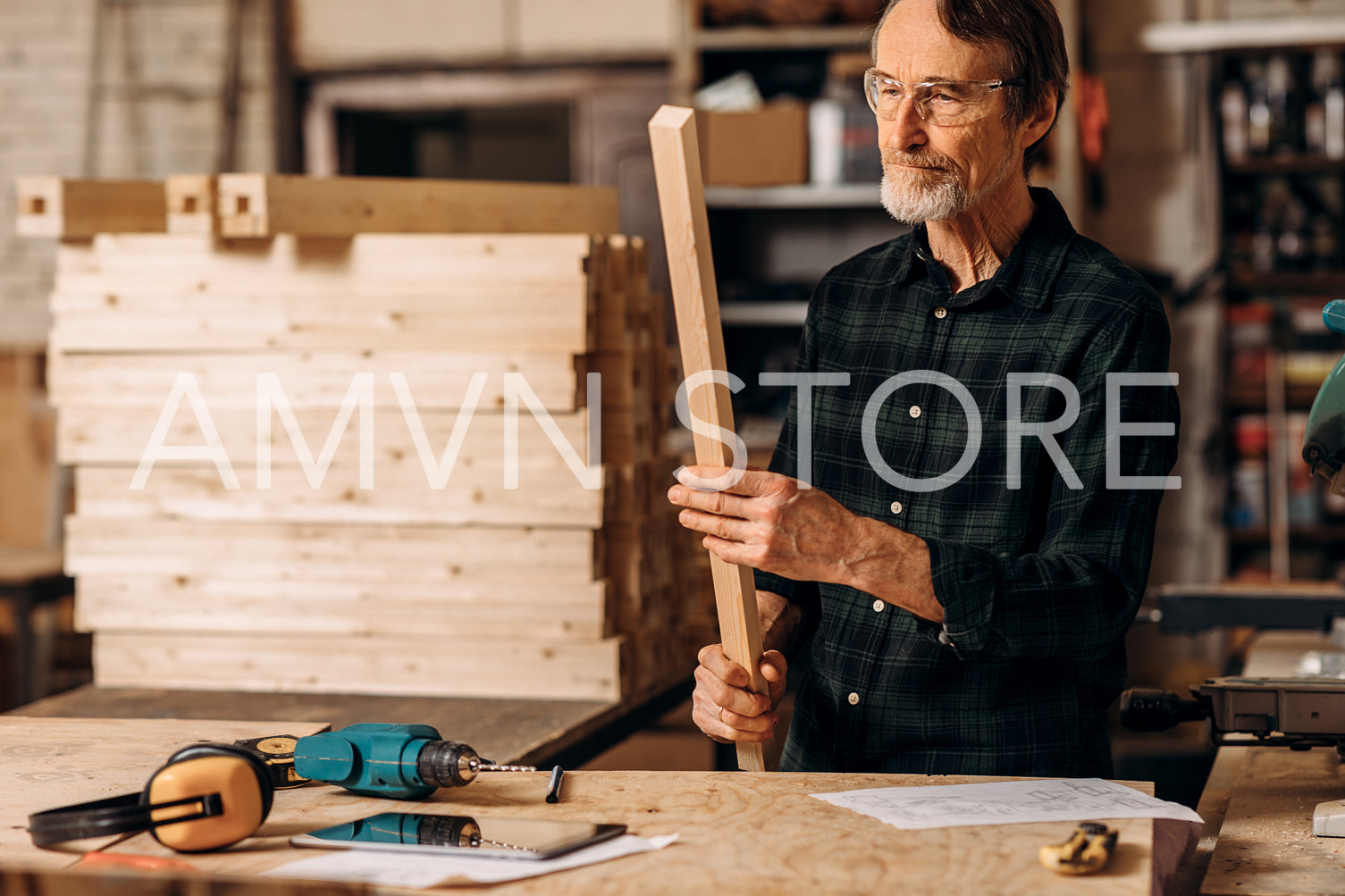 Senior carpenter wearing glasses holding a wood plank	