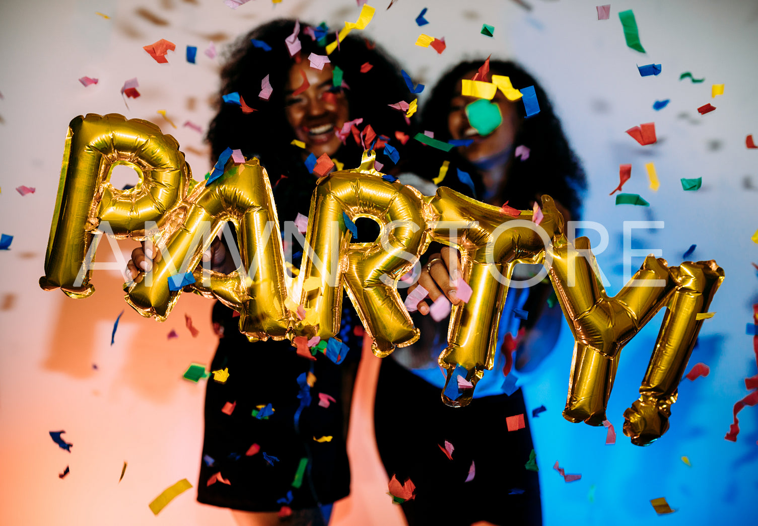 Happy girls standing near a wall under confetti	