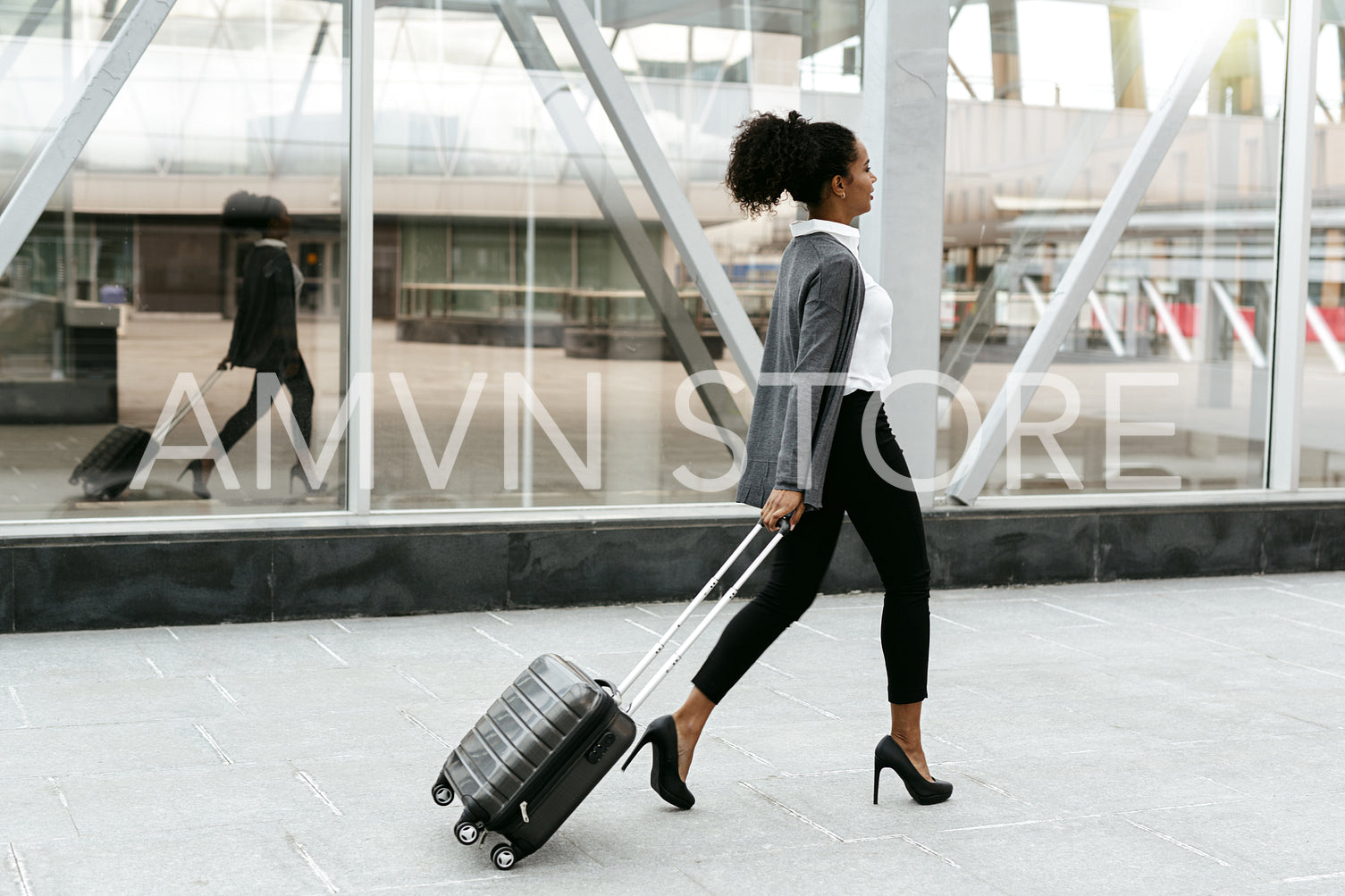 Travelling businesswoman walking with luggage at station, side view	