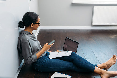 Side view of an entrepreneur woman holding a smartphone and looking on a laptop screen