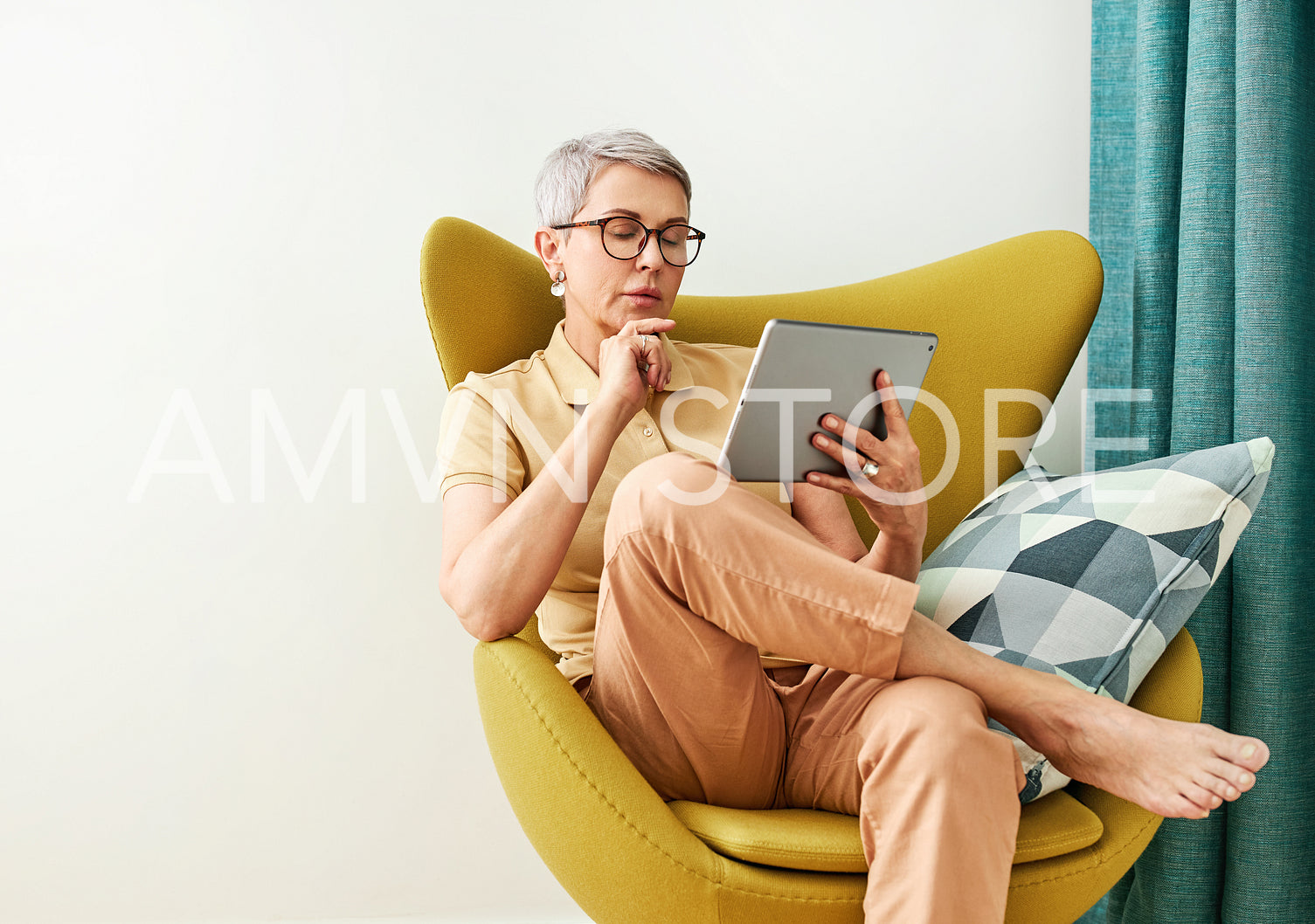 Thoughtful mature woman with closed eyes sitting at home holding a digital tablet