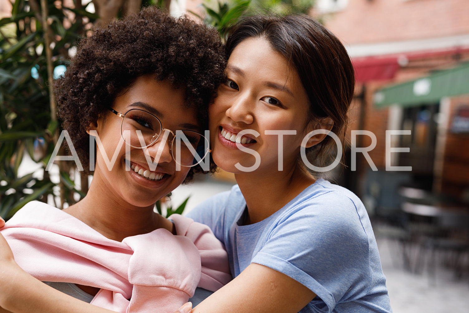 Two smiling friends looking at a camera, standing outdoors	