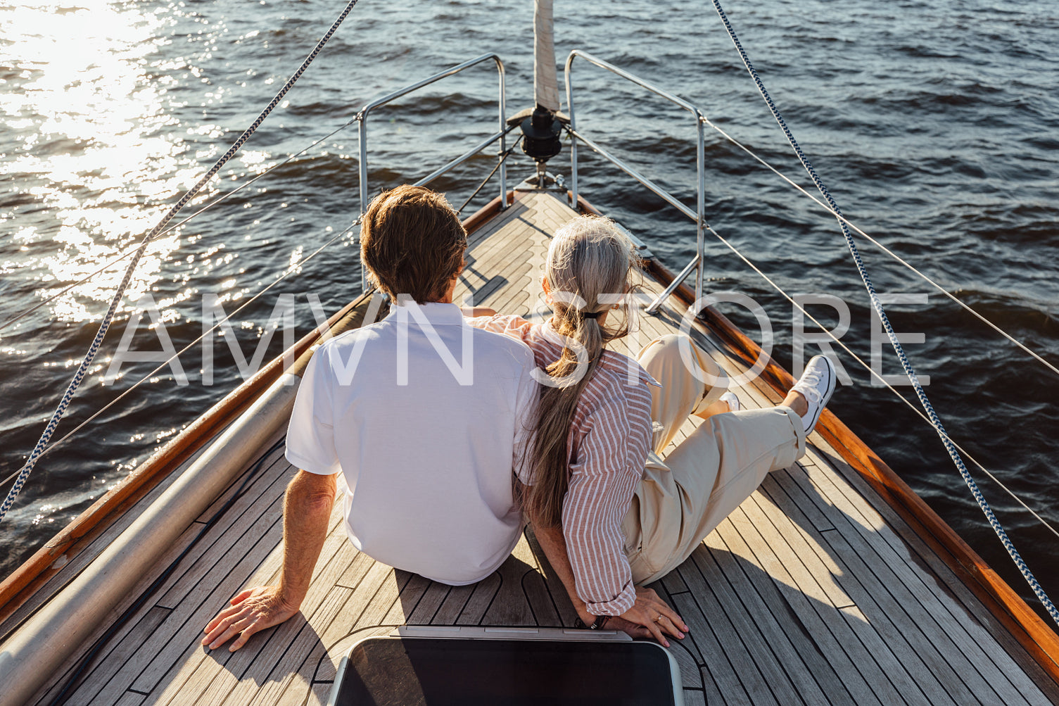 Rearview of two mature people sitting on a yacht bow. Loving senior couple enjoying a boat trip.	