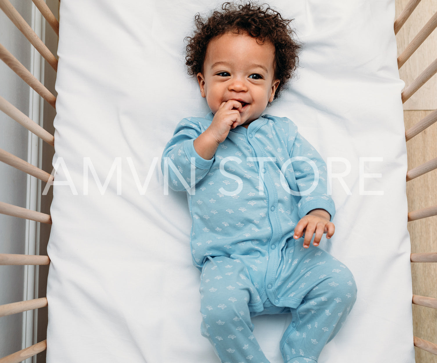 Overhead view of a happy baby boy lying in a crib wearing pajamas	